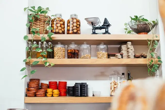 A beautifully organized kitchen pantry with glass jars and labels—organize a pantry on a budget. the Leaf Nest